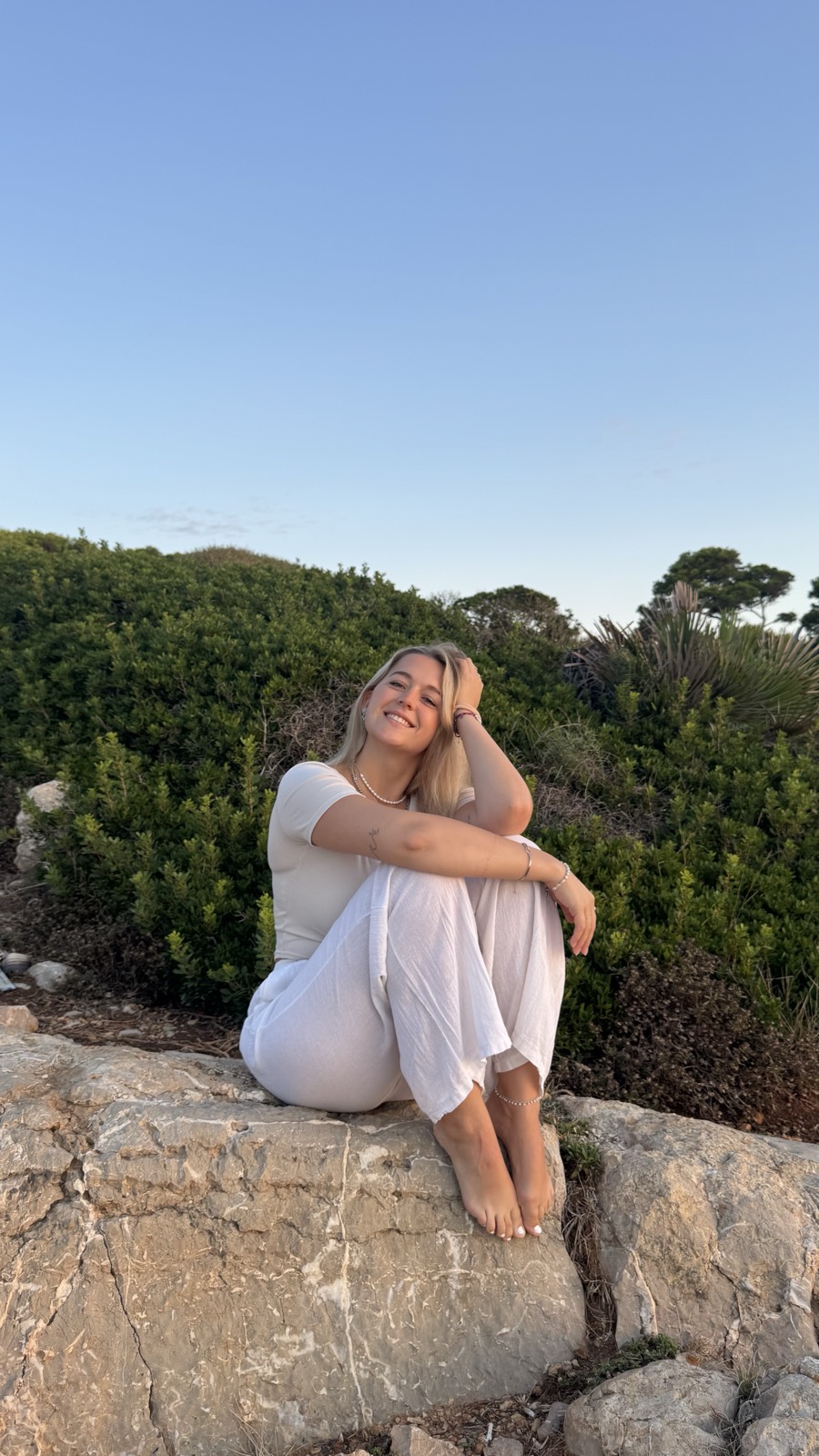 Nina Leismann sitzt entspannt auf einem Felsen in der Abendsonne und lächelt